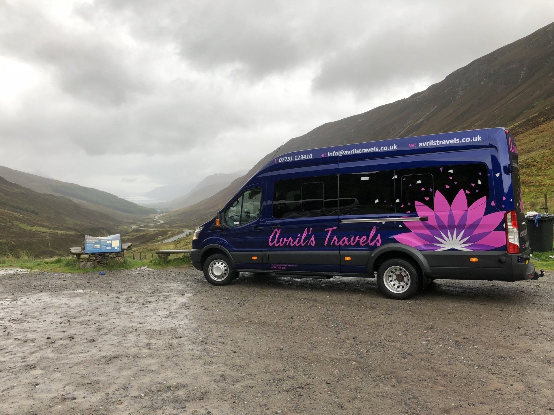 A blue van with a pink flower on the side is parked in a parking lot.