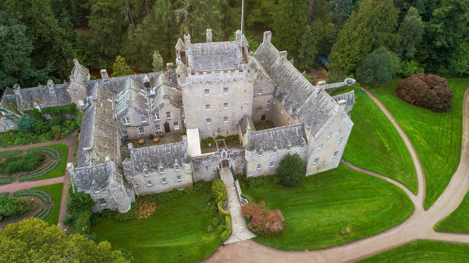 An aerial view of a large castle surrounded by trees and grass.