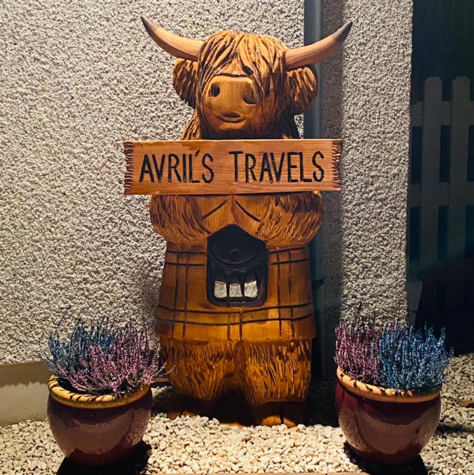 A statue of a cow holding a sign that says avril 's travels