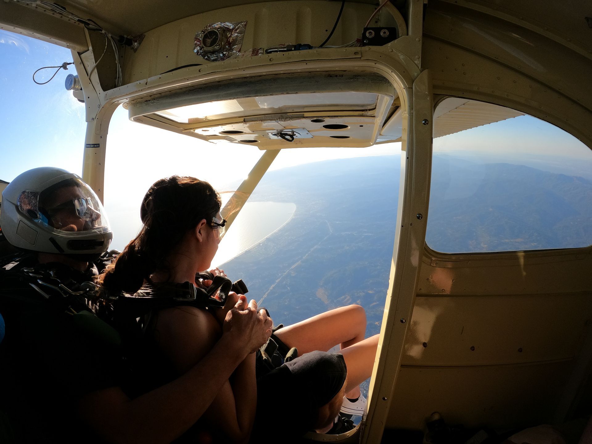 Skydive Santa Cruz tandem pair climb out of the airplane to prepare for a skydive at sunset. 