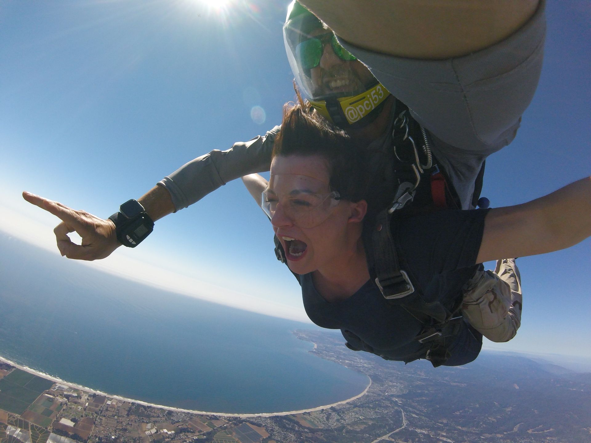 Skydive Santa Cruz tandem instructor points to the horizon for the tandem student. 