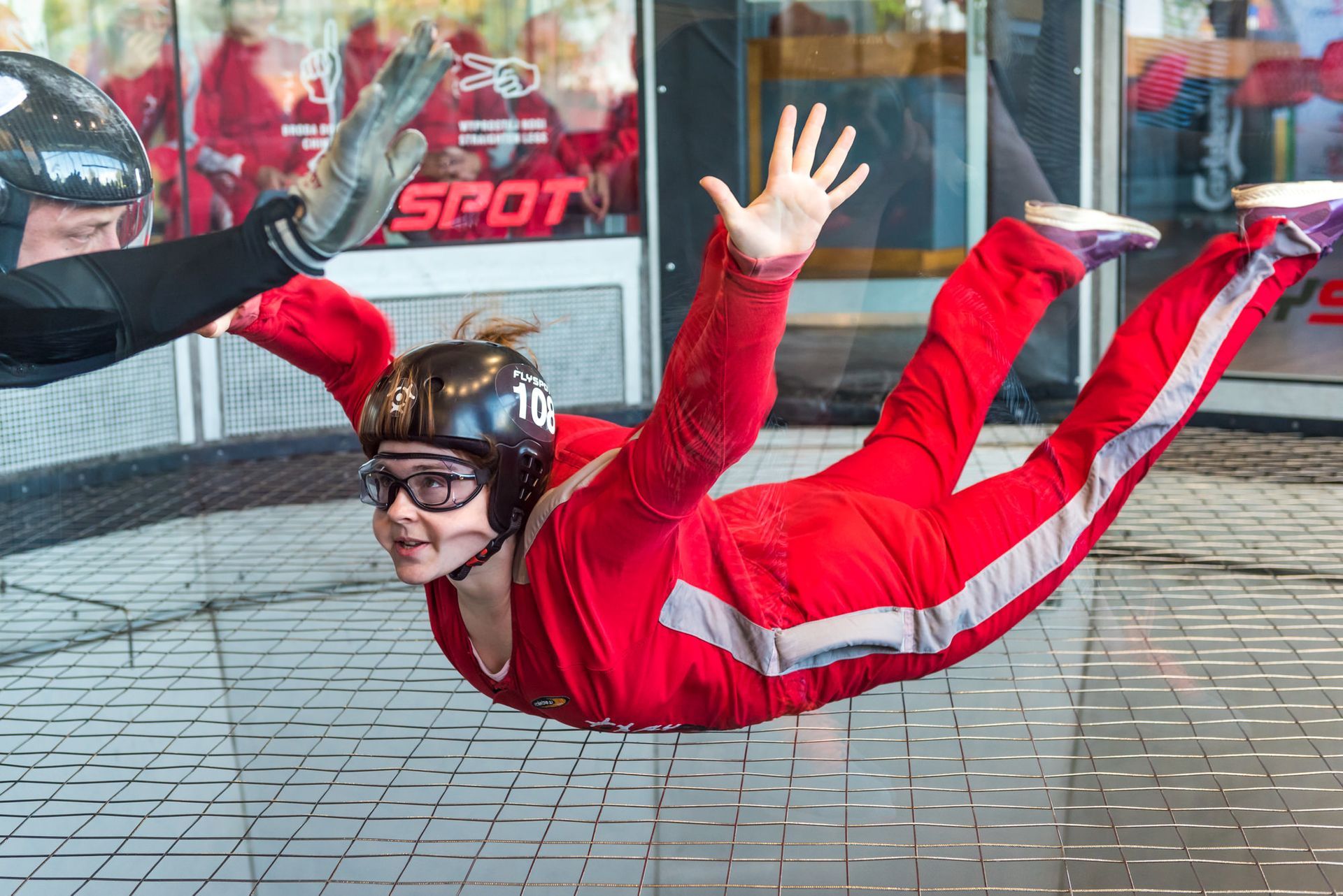 Woman does Indoor skydiving experience first time, floating above wind tunnel net 