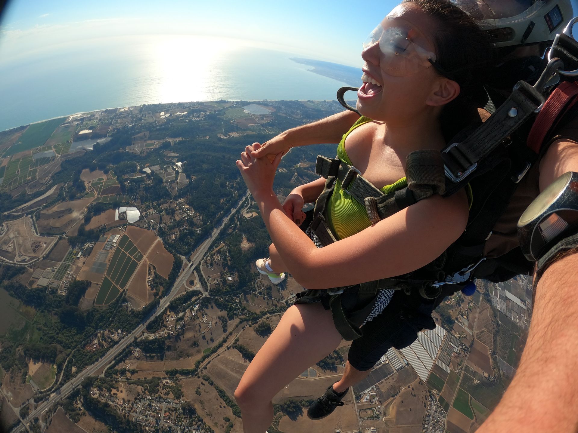 Tandem instructor and female student descent under parachute next to the ocean at Skydive Santa Cruz. 