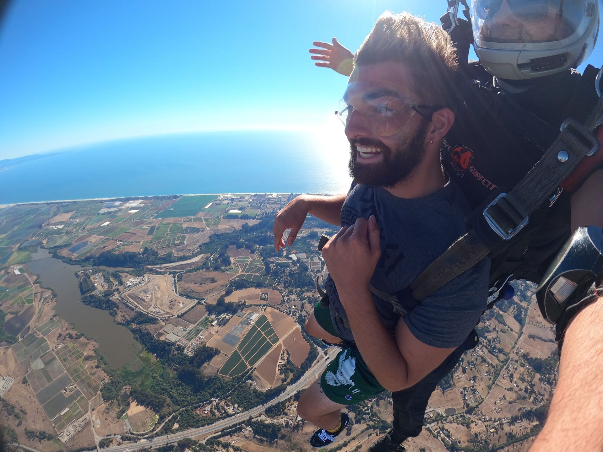 Skydive Santa Cruz tandem skydive pair descent under parachute next to the ocean.