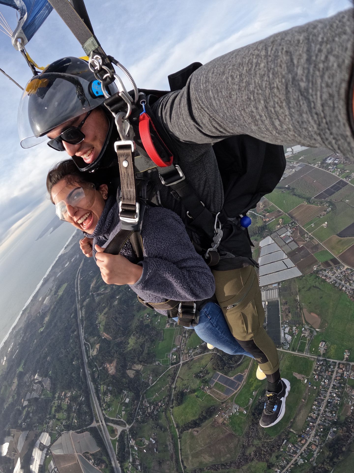 A man and a woman are flying through the air with a parachute over Skydive Santa Cruz.