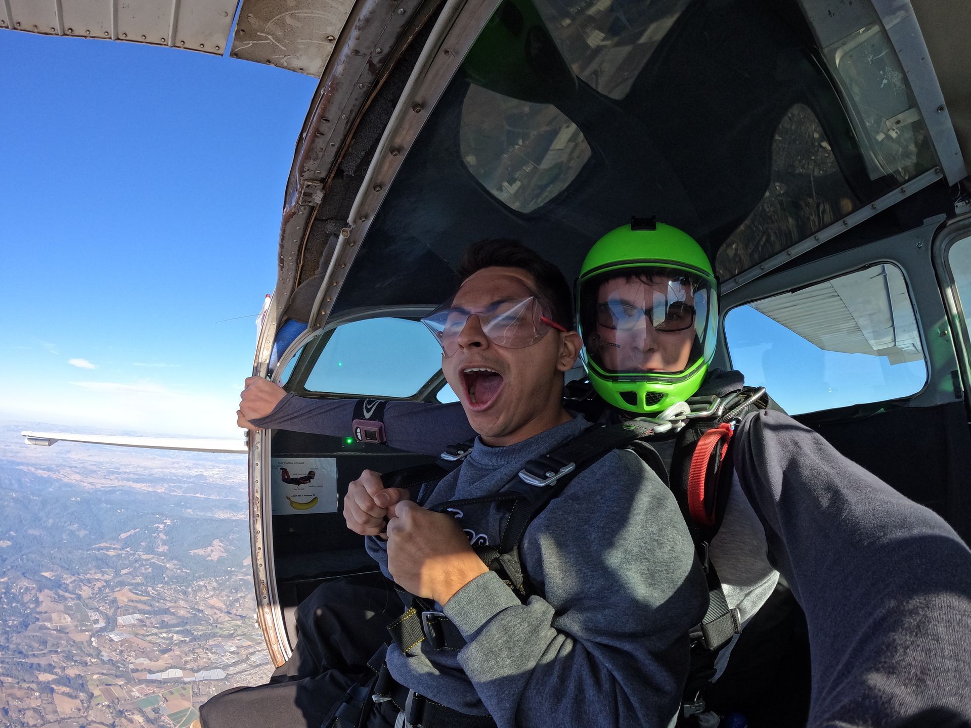 Tandem skydive pair prepare to exit from airplane over Skydive Santa Cruz. Student is very excited. 