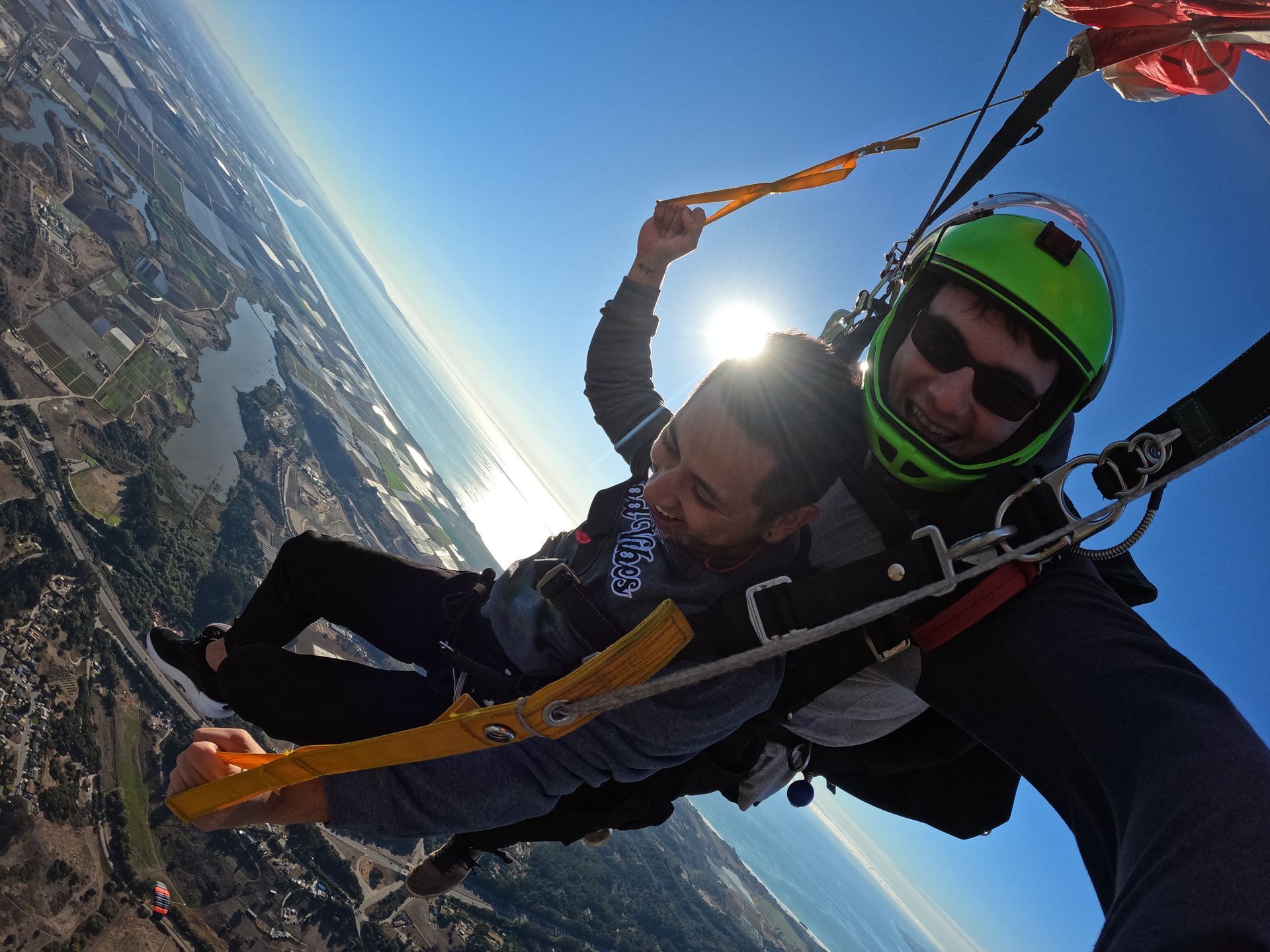 Tandem skydive pair make left turn under parachute as student pulls down on the controls over Skydive Santa Cruz. 