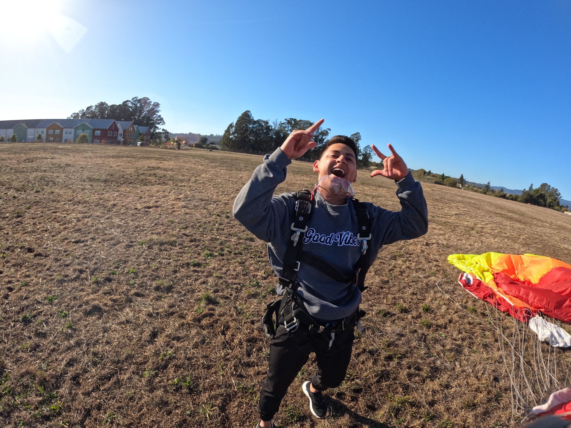 Skydive Santa Cruz student is standing in the landing zone with his hands in the air, stoked after his first skydive. 
