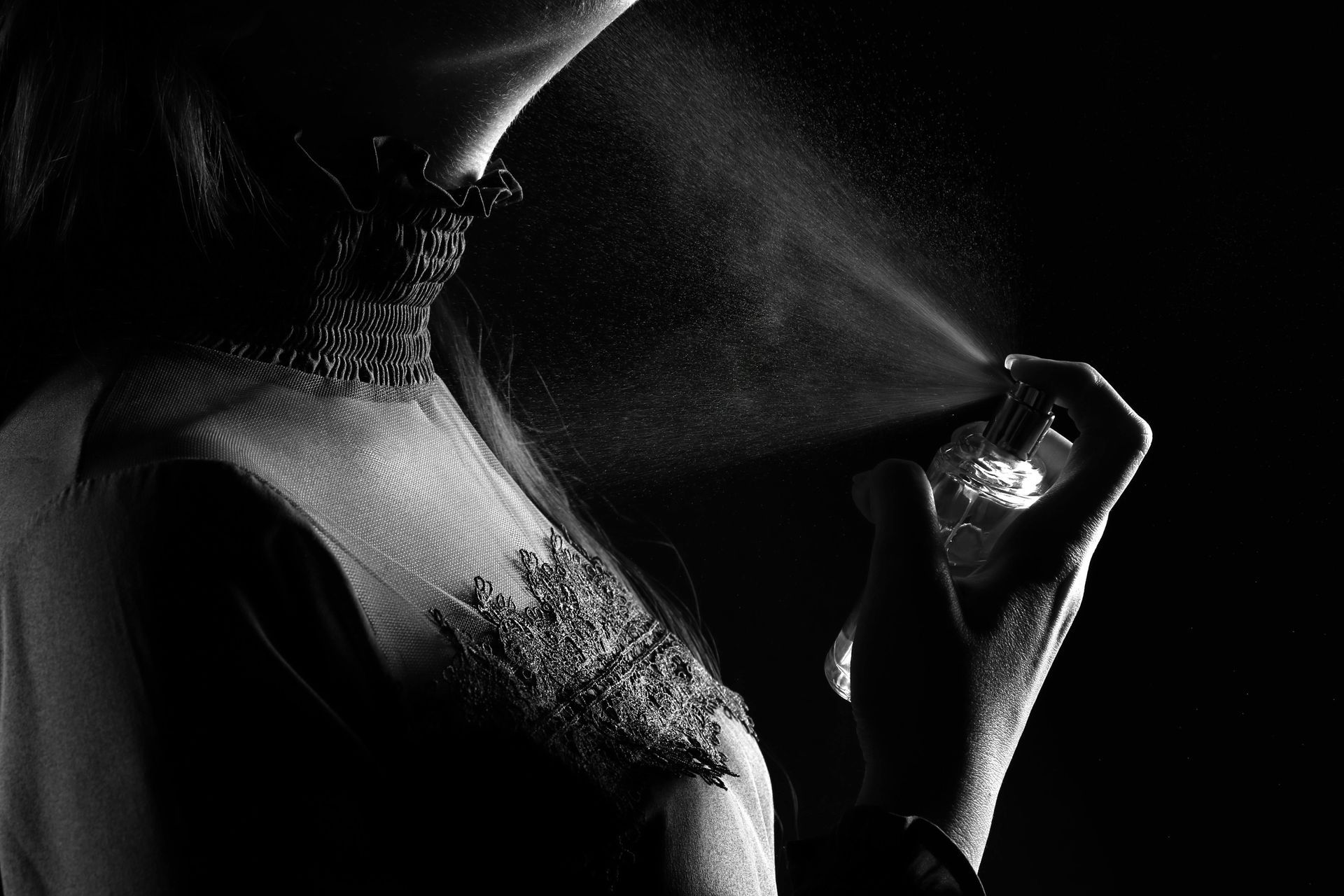 Frasco de perfume en blanco y negro, etiqueta “BLACKOU” y “OUD VANILLA”, sobre tela de satén oscuro.