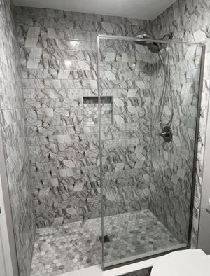 A bathroom with a walk in shower with a glass door.