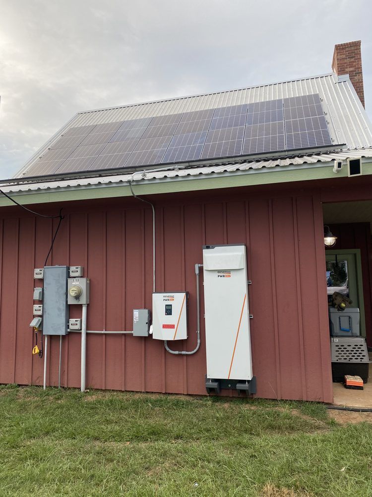 Solar panels on a red building with white energy storage and electrical boxes.