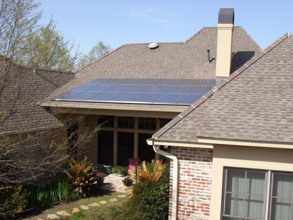 Solar panels on a residential rooftop, positioned near a chimney.