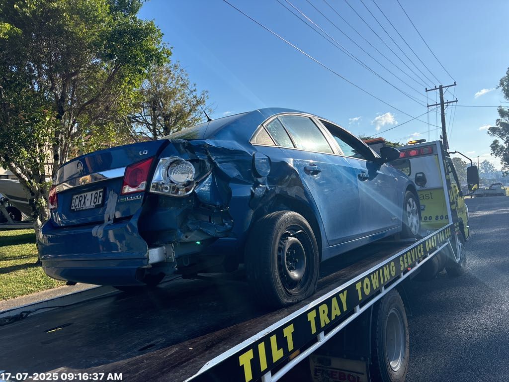 Blue Sedan Car Damaged on Tow Truck Cars in a Repair Shop — T & C Smash Repairs In Coffs Harbour, NSW