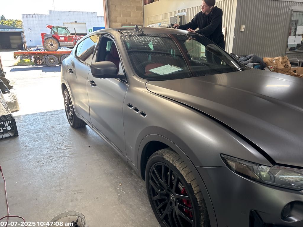 A Person Working on a Matte Gray Car in a Garage — T & C Smash Repairs In Coffs Harbour, NSW