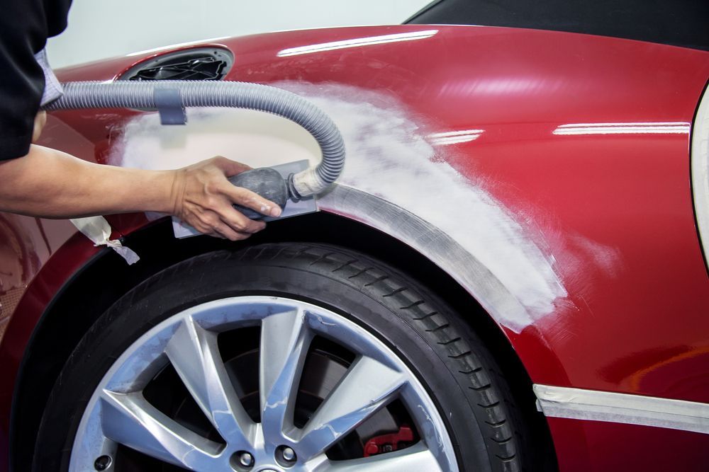 A Person is Sanding the Fender of a Red Car With a Sander — T & C Smash Repairs In Coffs Harbour, NSW