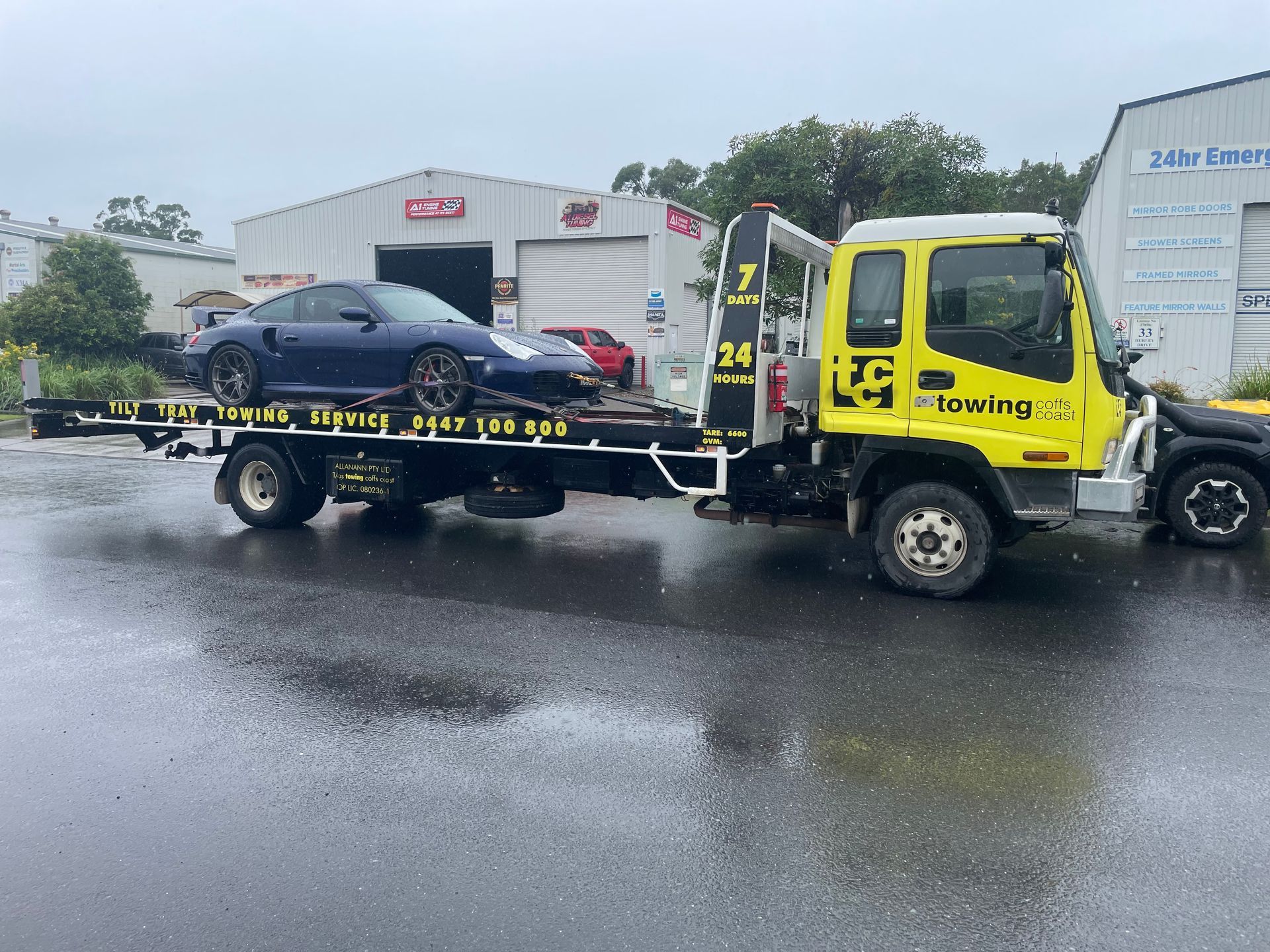 A Towing Truck With a Car on the Back of It — T & C Smash Repairs In Coffs Harbour, NSW