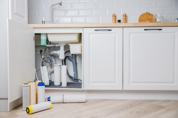 A kitchen sink with a water filter underneath it.