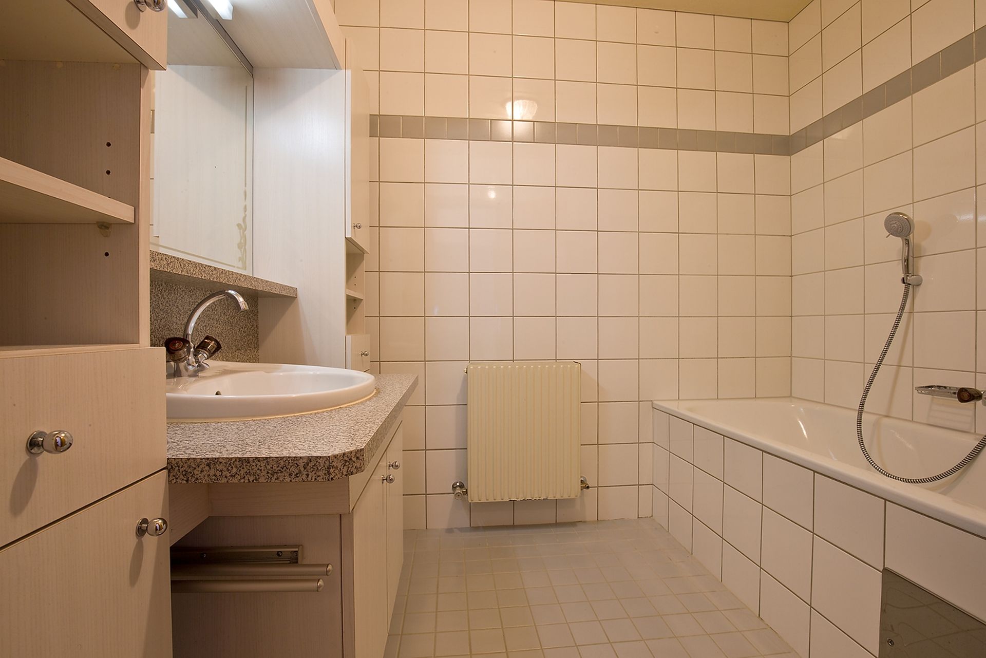 Ein Badezimmer mit weißen Fliesen und einem Waschbecken und einer Badewanne