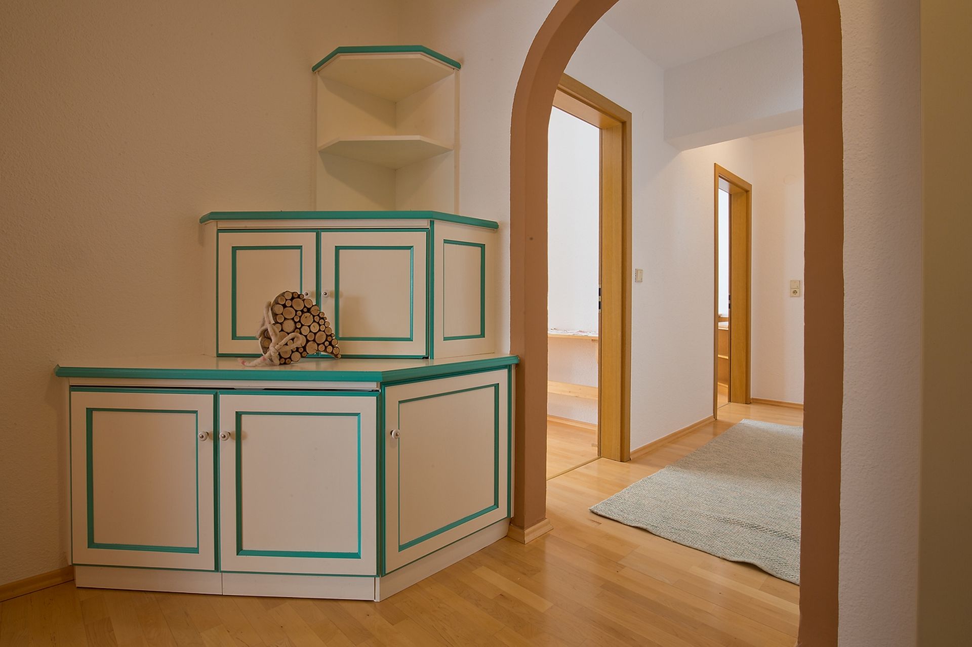 Ein Flur mit Eckschrank und Teppich