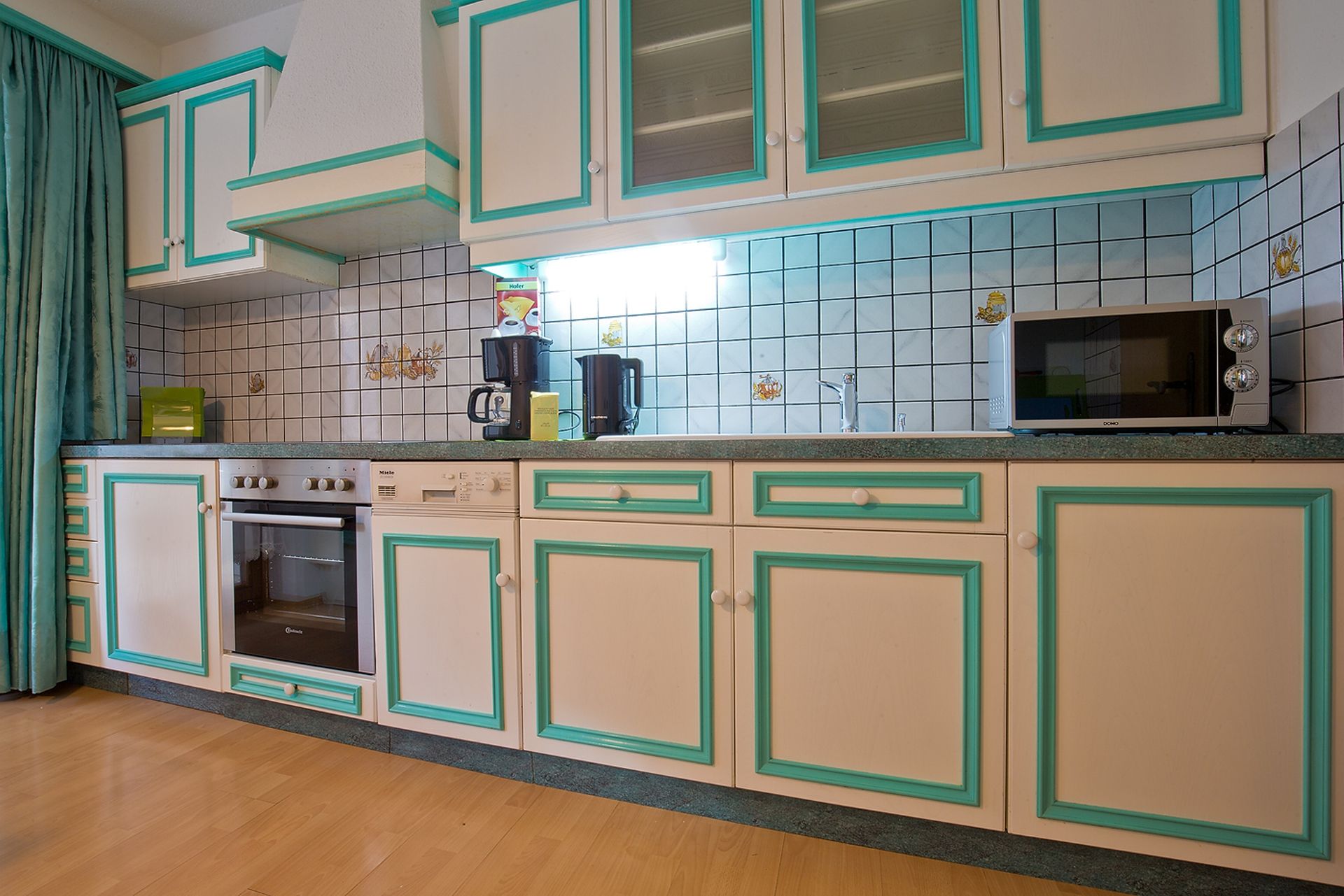 Eine Küche mit weißen Schränken und blauen Zierleisten