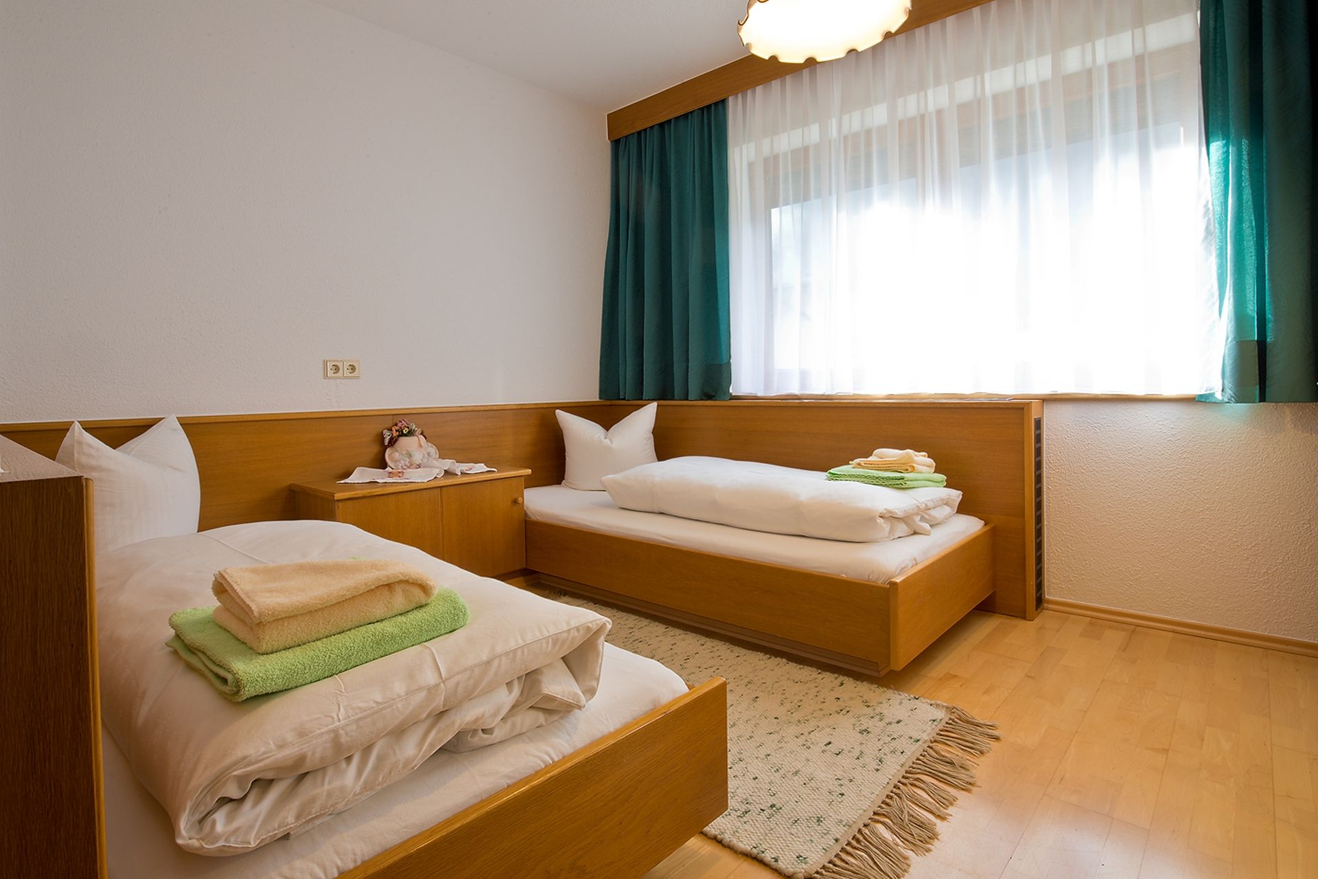 Ein Schlafzimmer mit zwei Betten und einem Fenster mit grünen Vorhängen