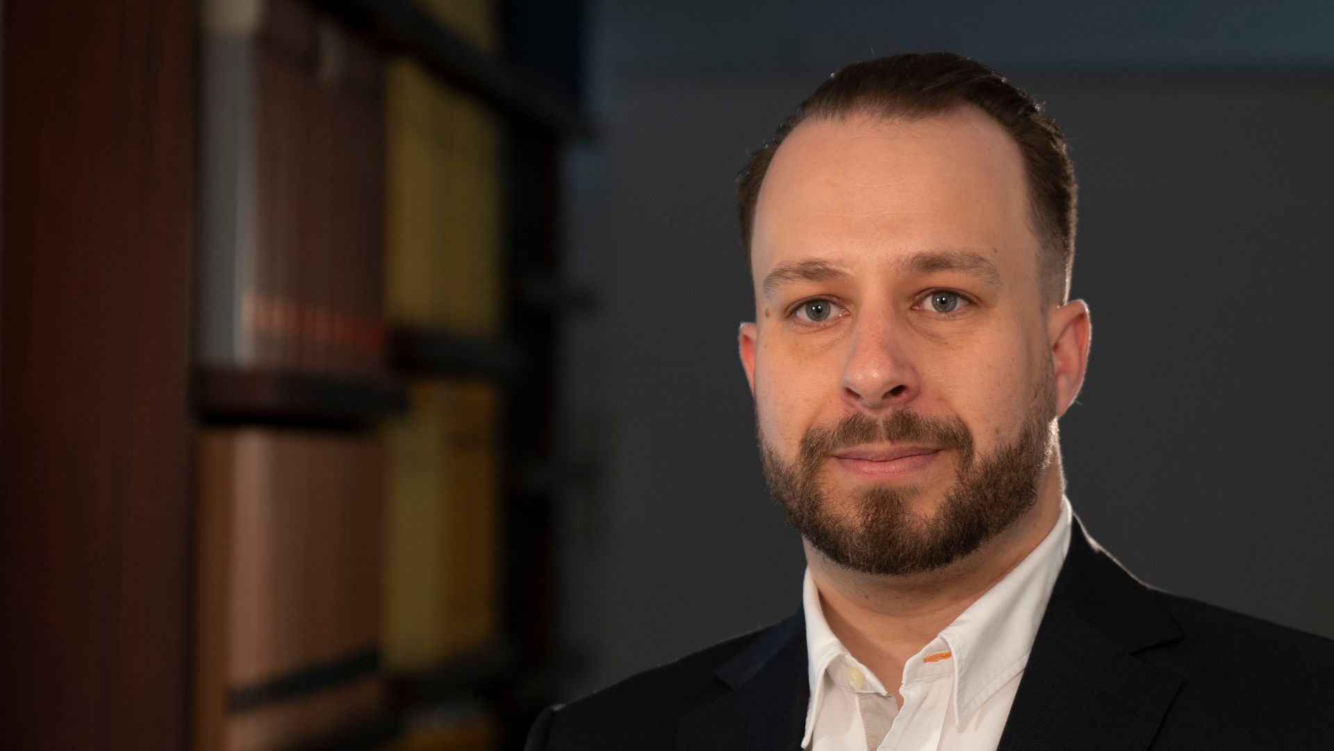 Ein Mann mit Bart trägt einen Anzug und ein weißes Hemd.