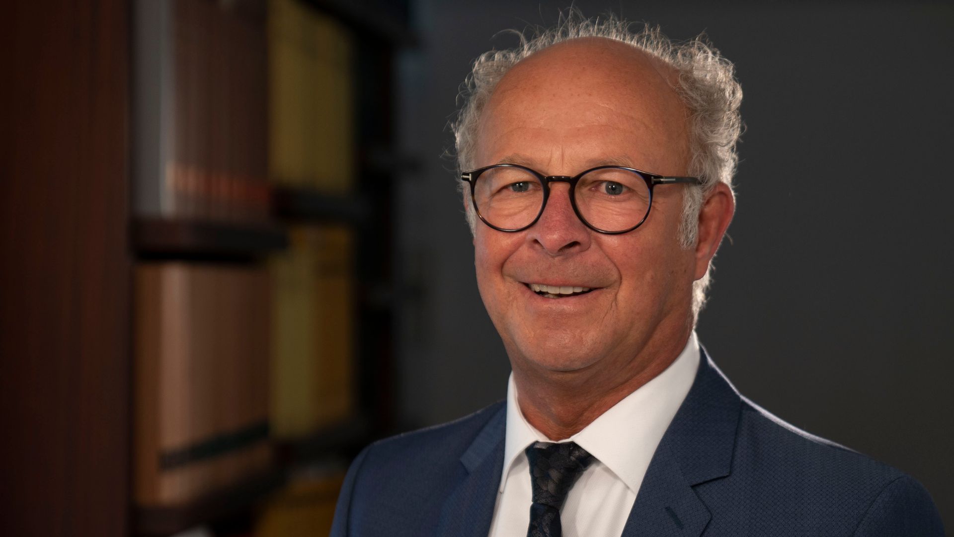 Ein Mann in Anzug und Krawatte lächelt in die Kamera.