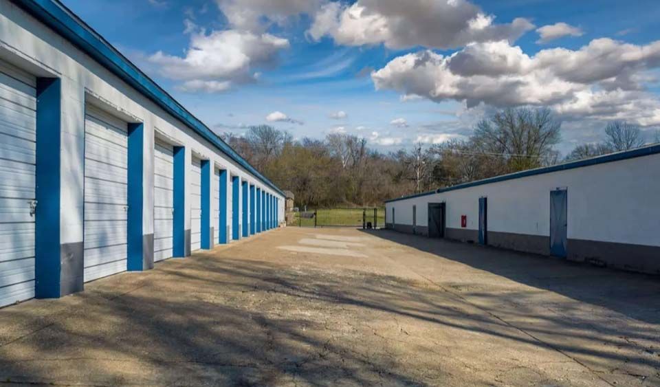 A row of storage units with blue and white doors on a sunny day.