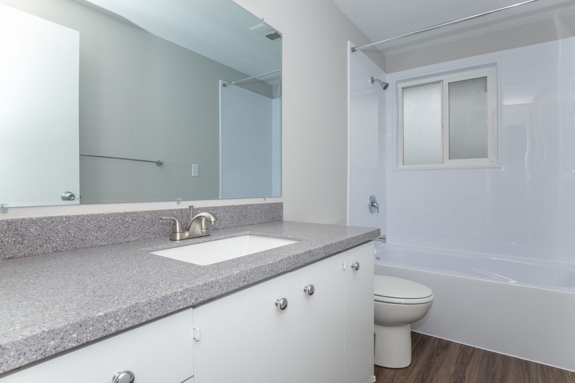 A bathroom with a sink , toilet , tub and mirror.