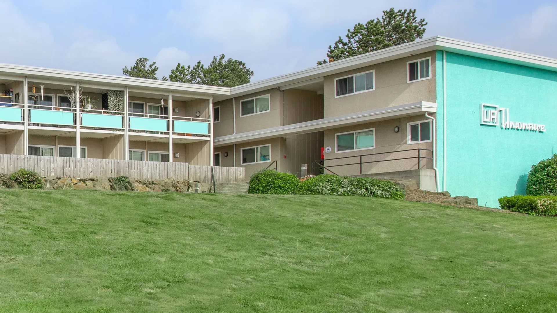 A large apartment building is sitting on top of a grassy hill.