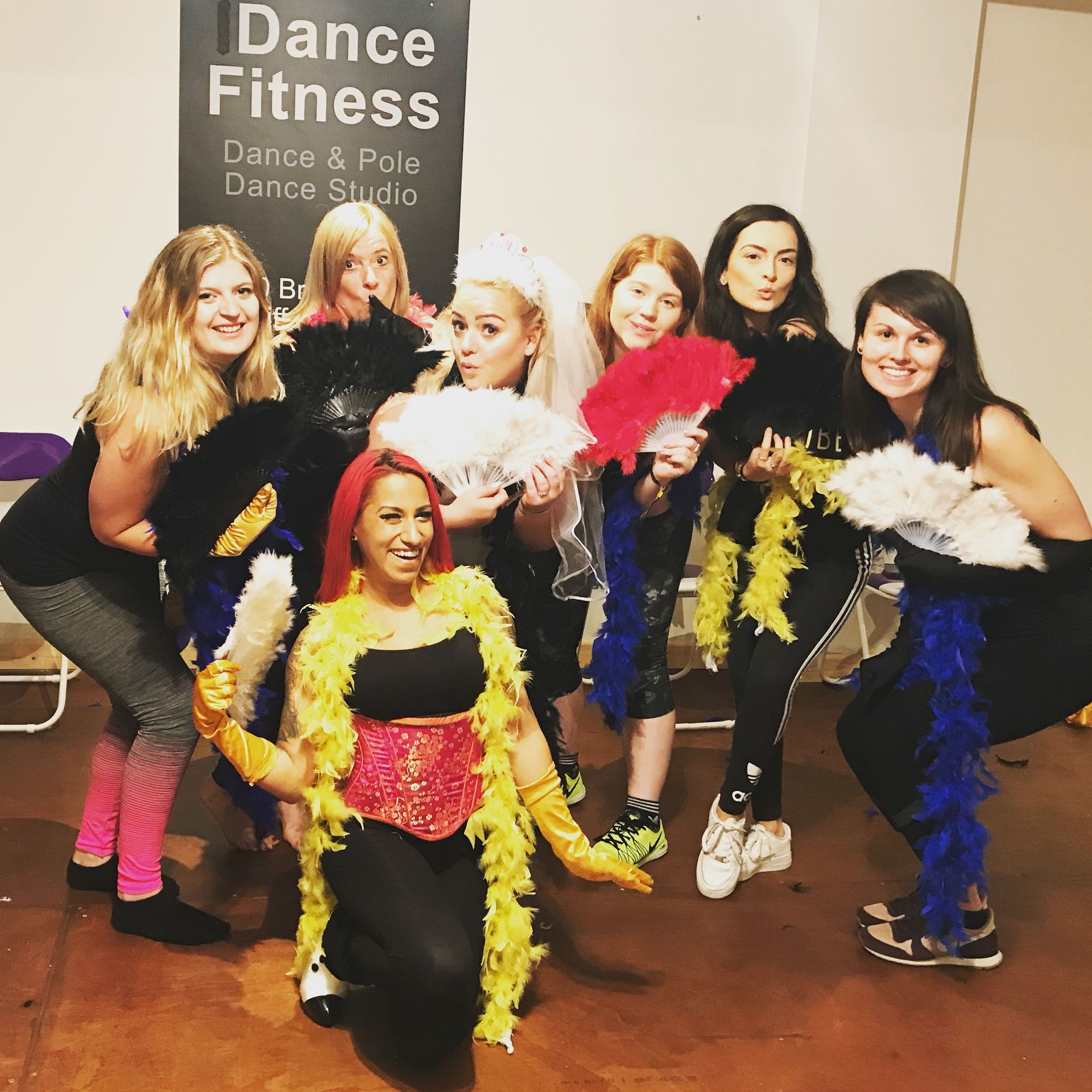 Bride-to-be and her friends posing with colourful feather boas and fans during a fun indoor burlesque hen party dance class in Cardiff