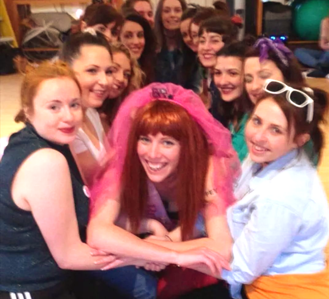 Happy hen party group posing with the bride after a lively themed dance class in a Cardiff studio