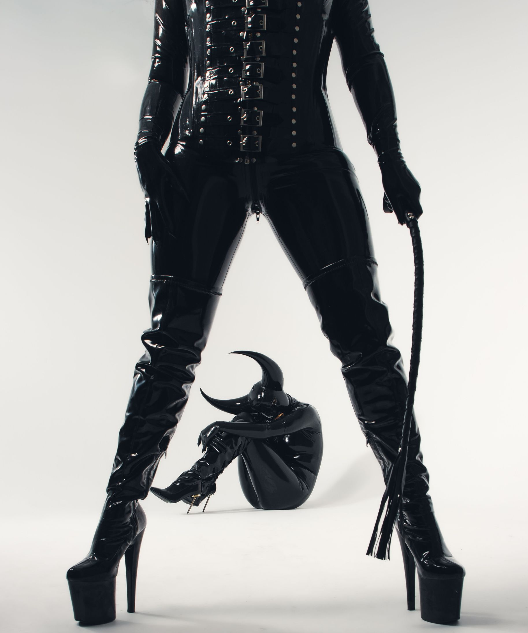 Professional female dominatrix holding a riding crop while her male submissive kneels obediently between her legs during a fun, interactive Dominatrix & Sub Experience by Epic Moments UK.