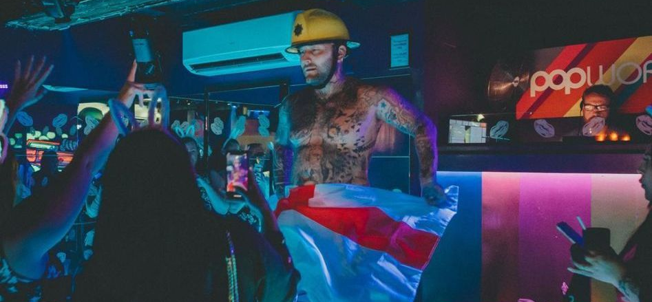 Male strip performer entertaining a hen party crowd during a themed stage show