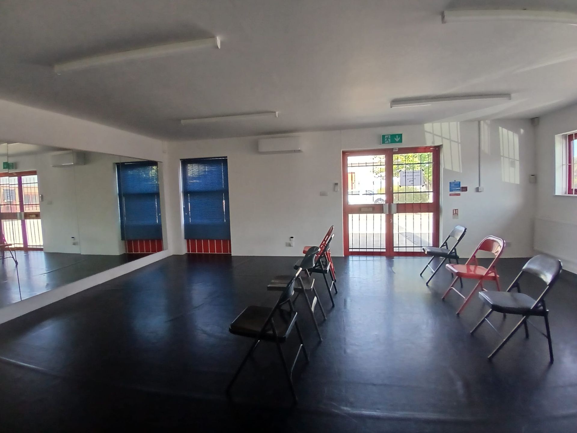 Dance studio set up for a chair tease workshop with black and red folding chairs arranged on a black floor in front of a full wall mirror