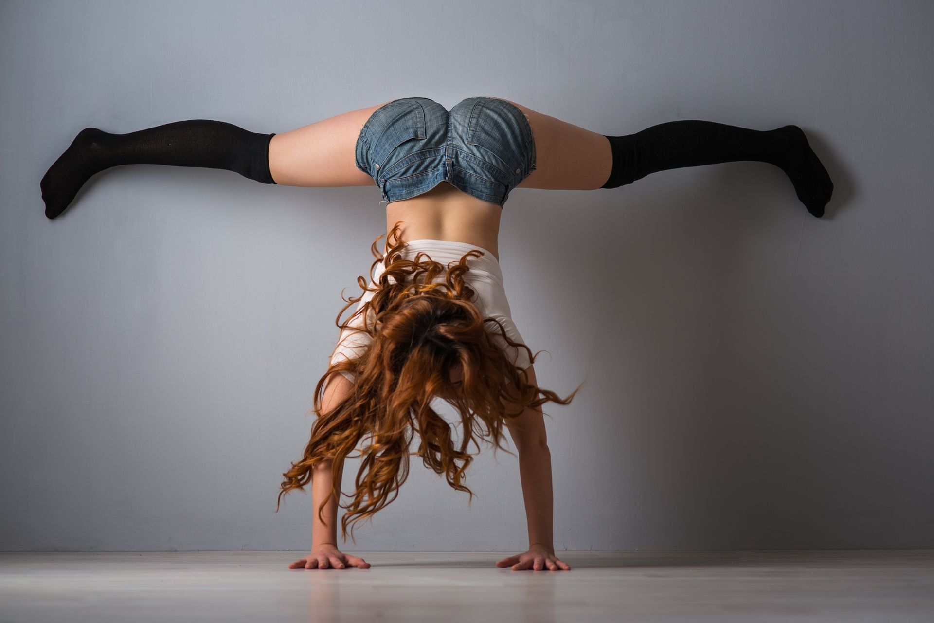 Female dancer practising a twerk handstand pose against a wall during a twerk and pole workshop in Cardiff