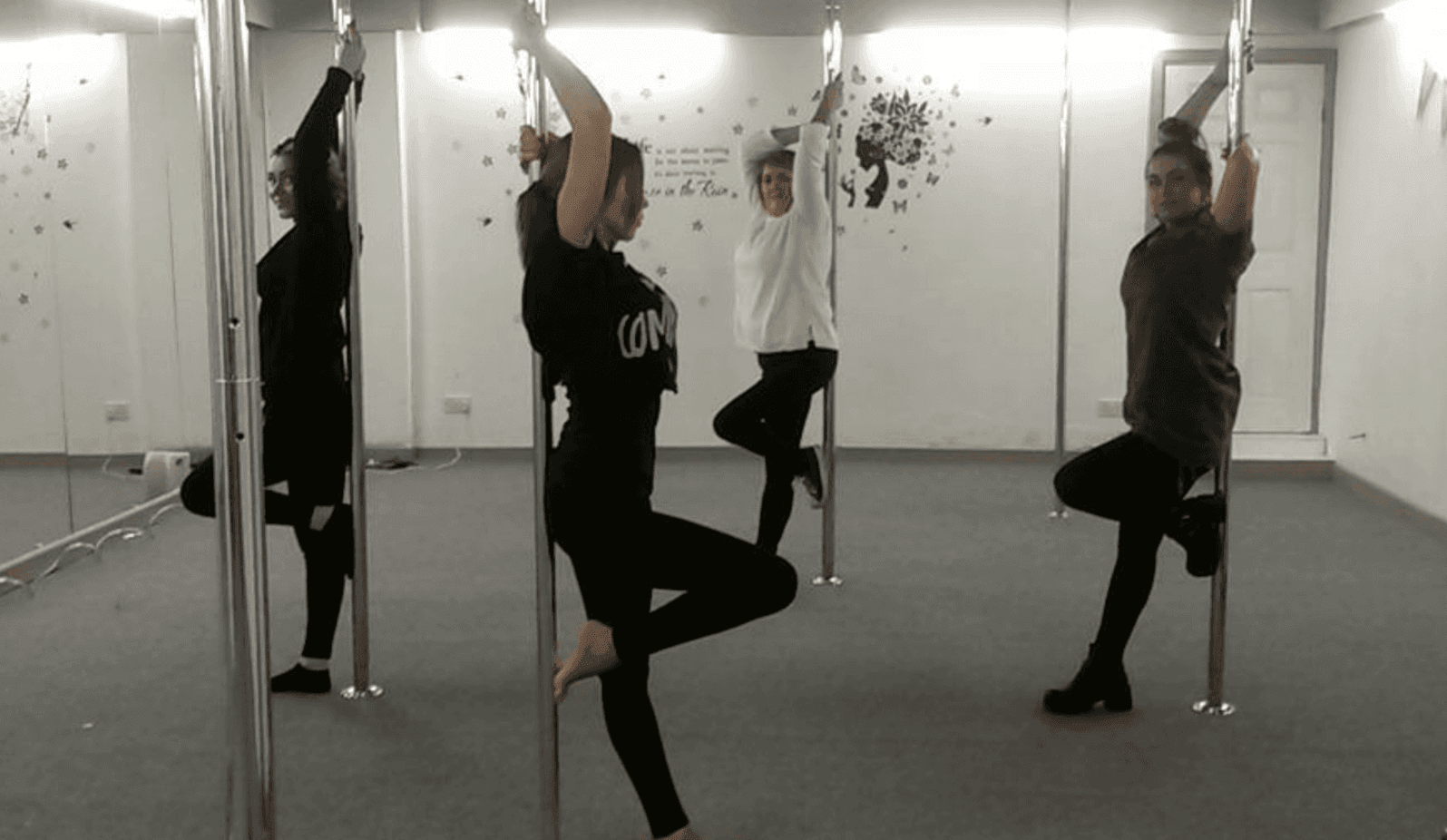 Group learning basic pole dance moves and practising an easy routine together in a Cardiff studio