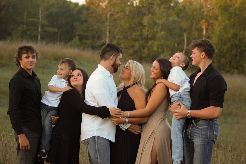 A large family is posing for a picture in a field.