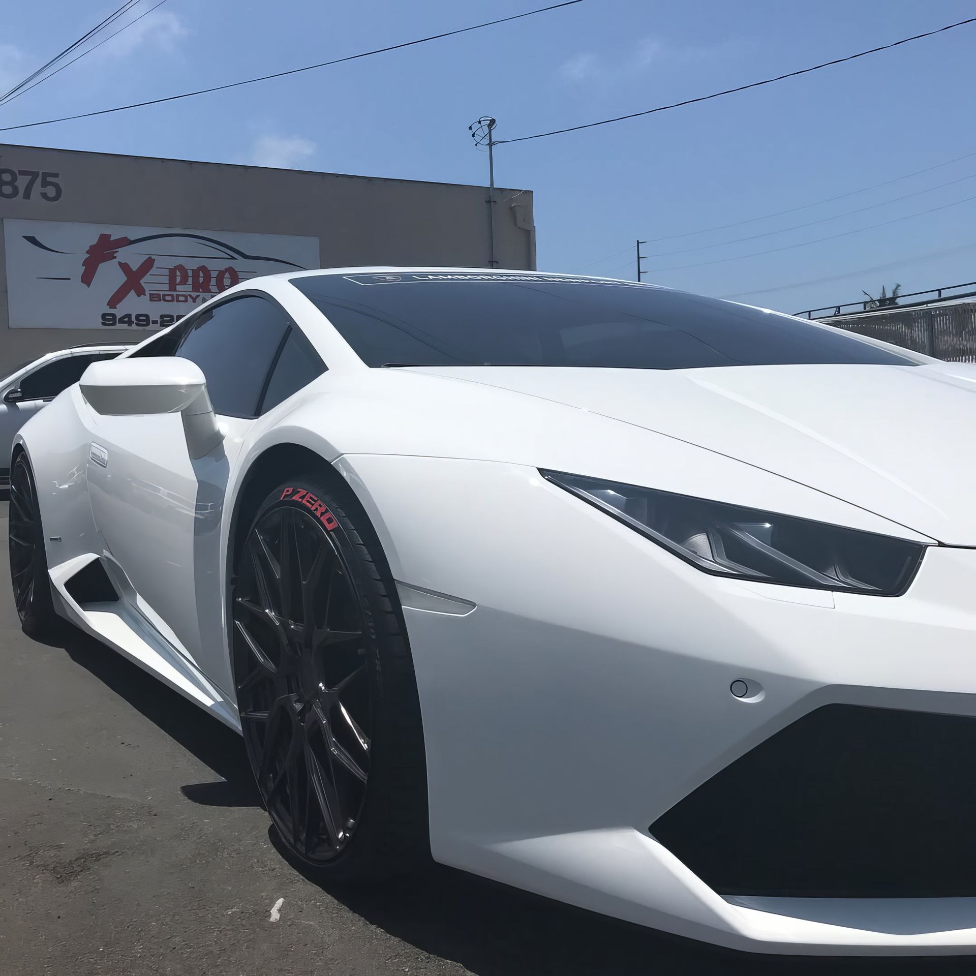 White sports car parked outdoors on a sunny day, front-left view with black wheels and sharp angular styling