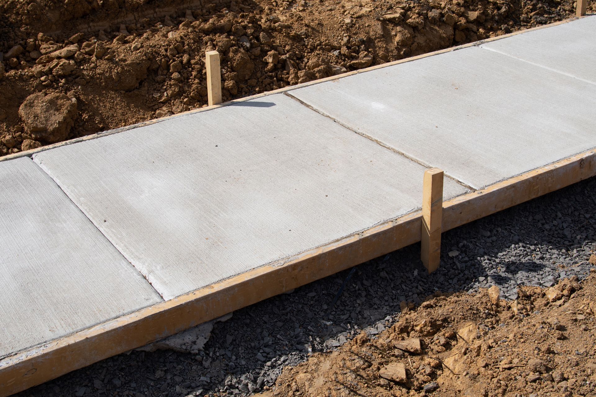 Freshly poured concrete sidewalk sections with wooden forms.