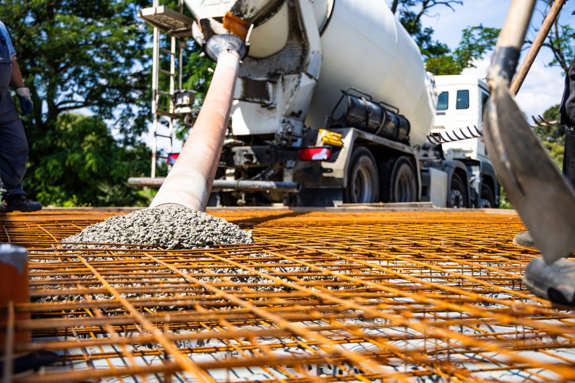 Cement truck pouring concrete onto rebar grid at construction site.