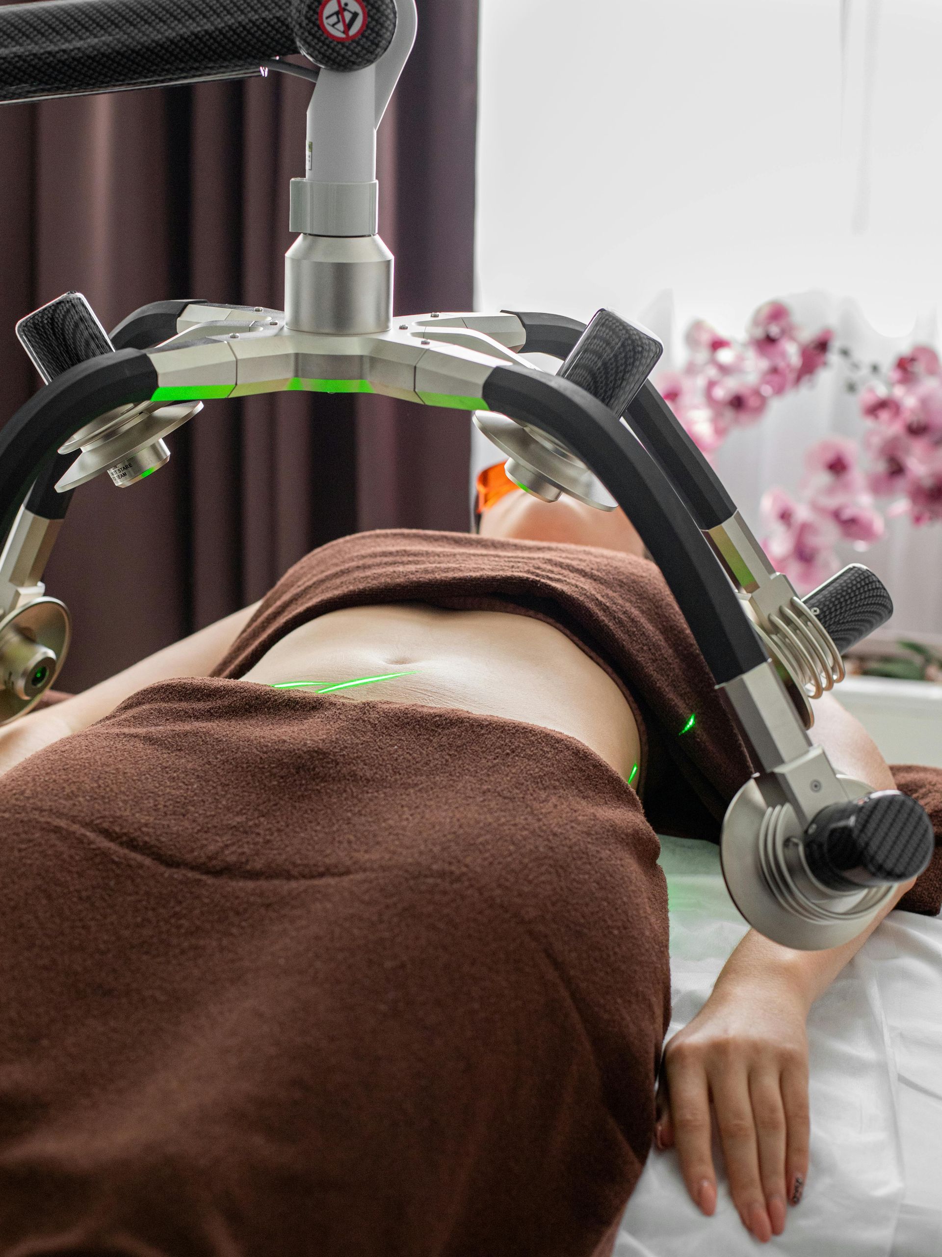 A woman laying on a bed with a machine on her stomach.