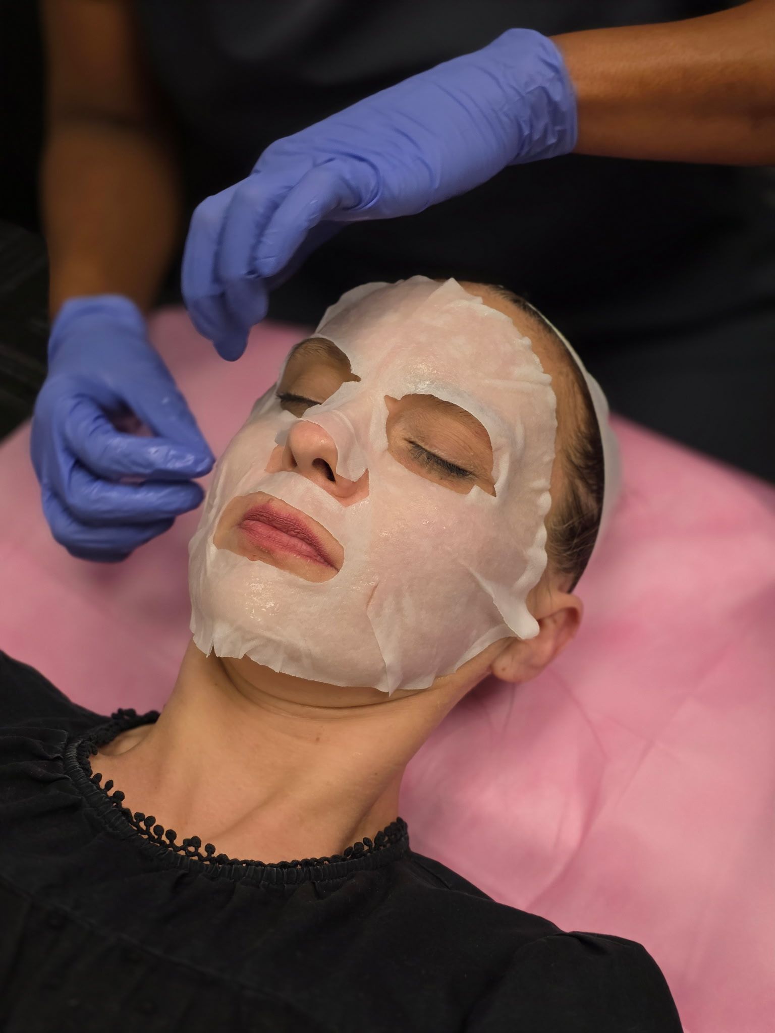 Person with face mask lying down while someone adjusts it with blue gloves.
