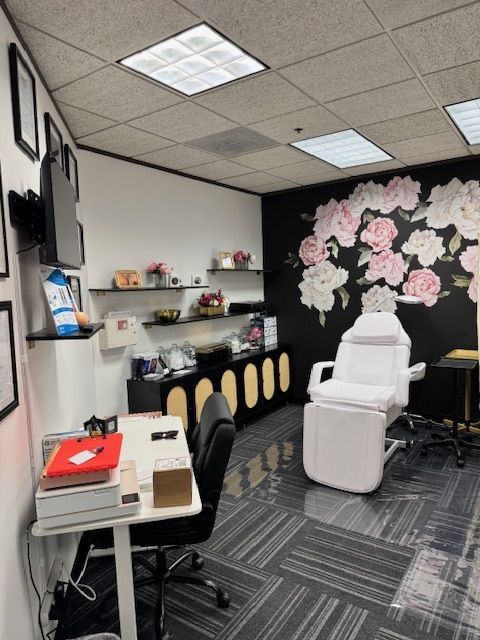 Salon treatment room with a black floral mural and white treatment chair.