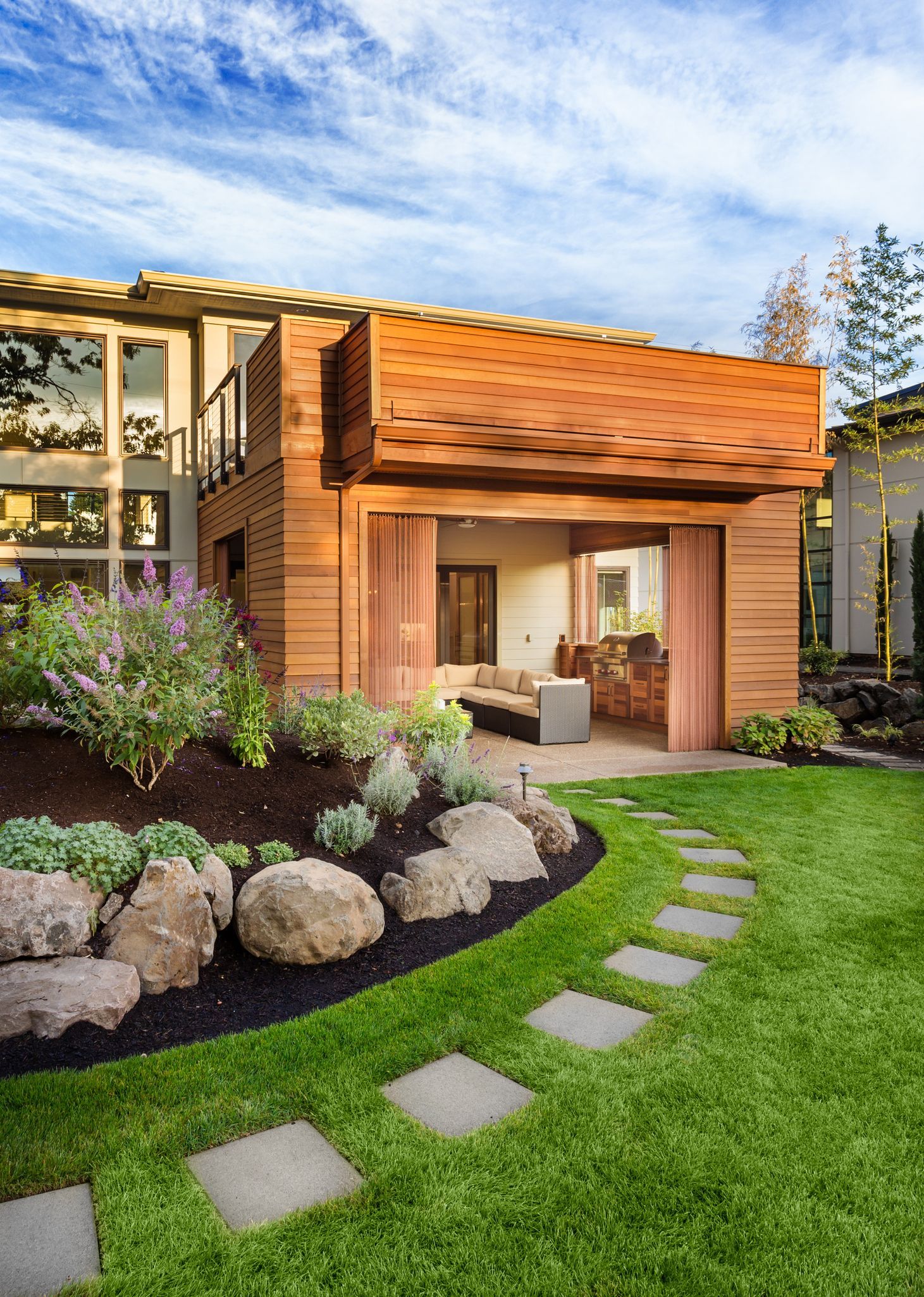 A house with a lush green lawn and a stone walkway leading to it.