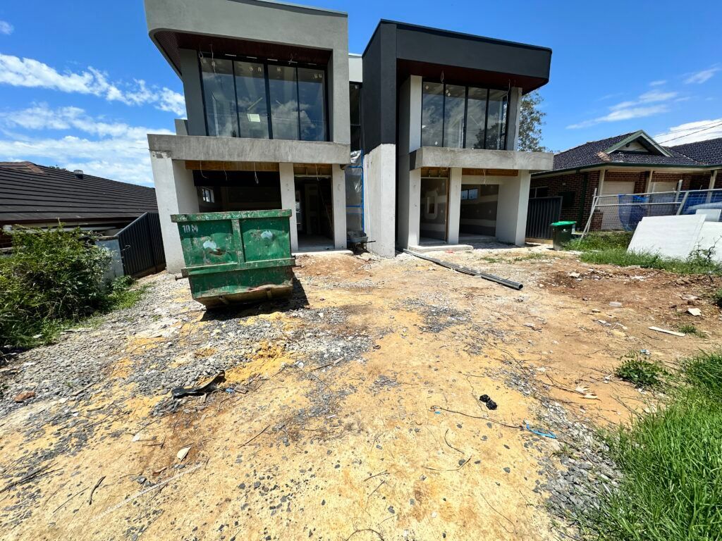 A large house under construction with a green dumpster in front of it.