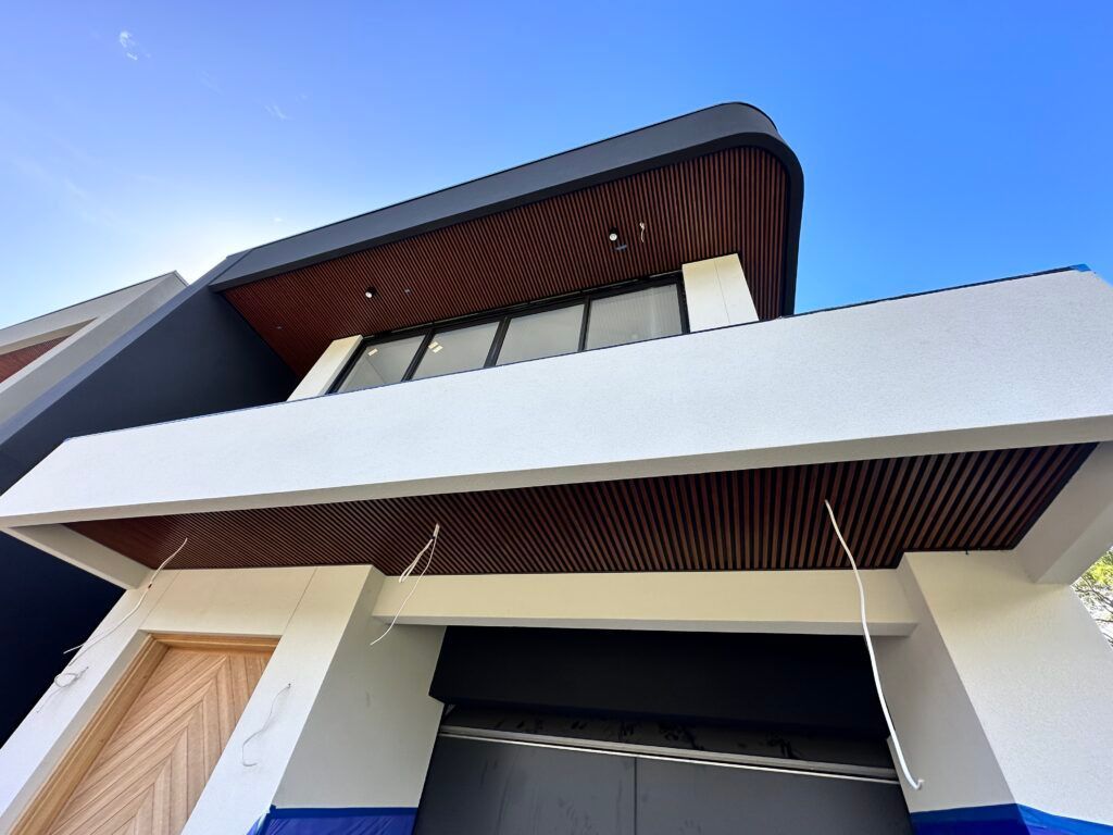 Looking up at a modern house with a blue sky in the background.