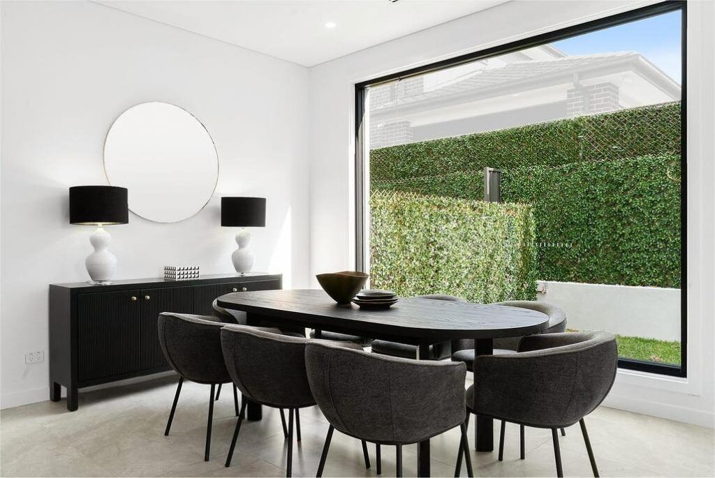 A dining room with a table and chairs and a large window.