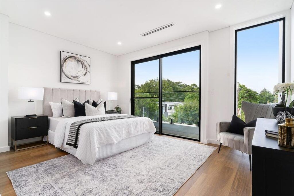 A bedroom with a large bed , chair , nightstand and sliding glass doors.