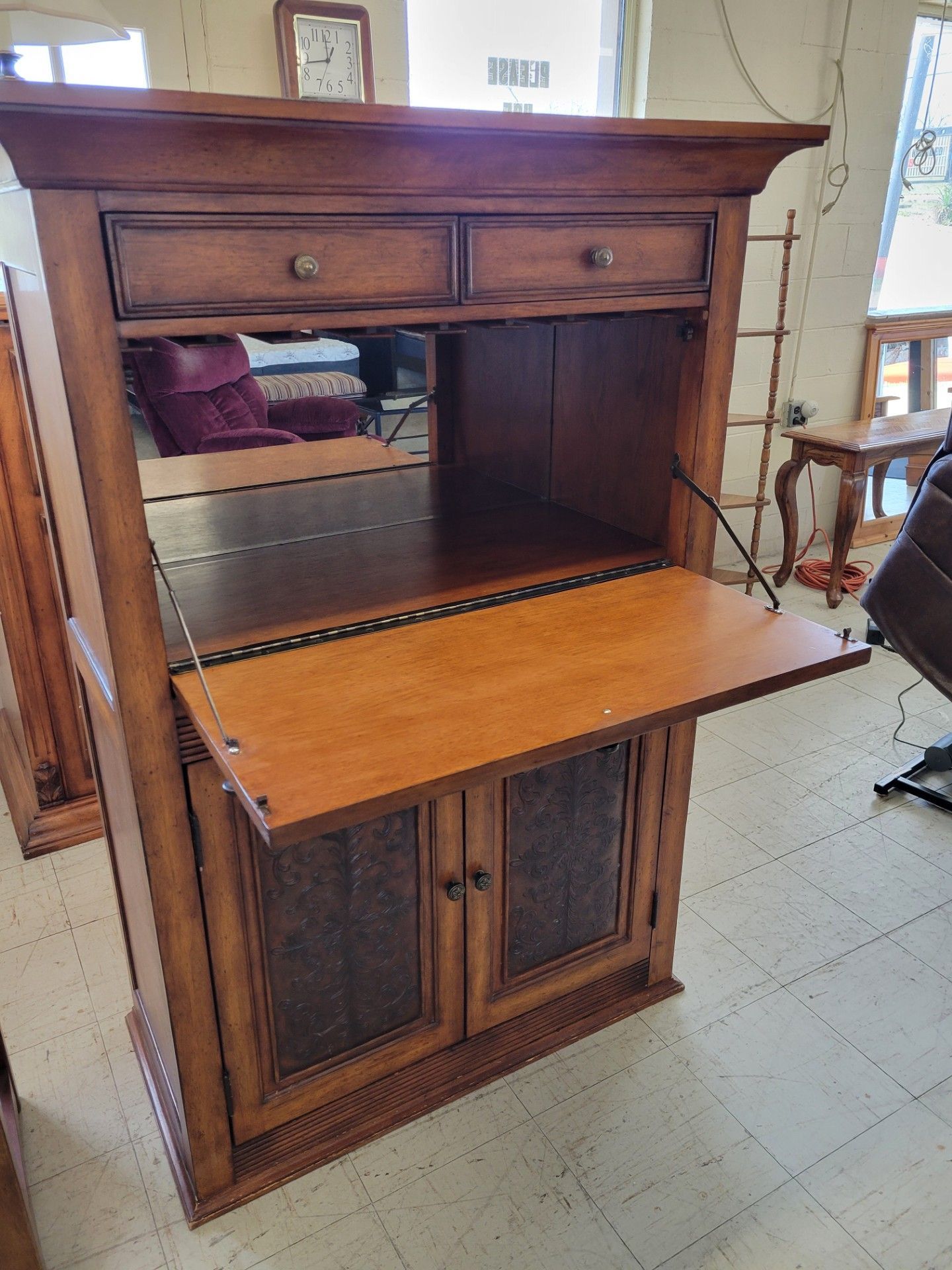 Wooden bed frame with mattress in a store setting. A red chair is in front.